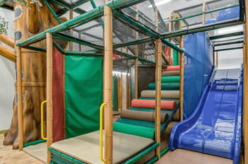 a view of the climbing structure with a blue slide on the left and a red slide on  at Harbor Pointe, Bayonne, 07002